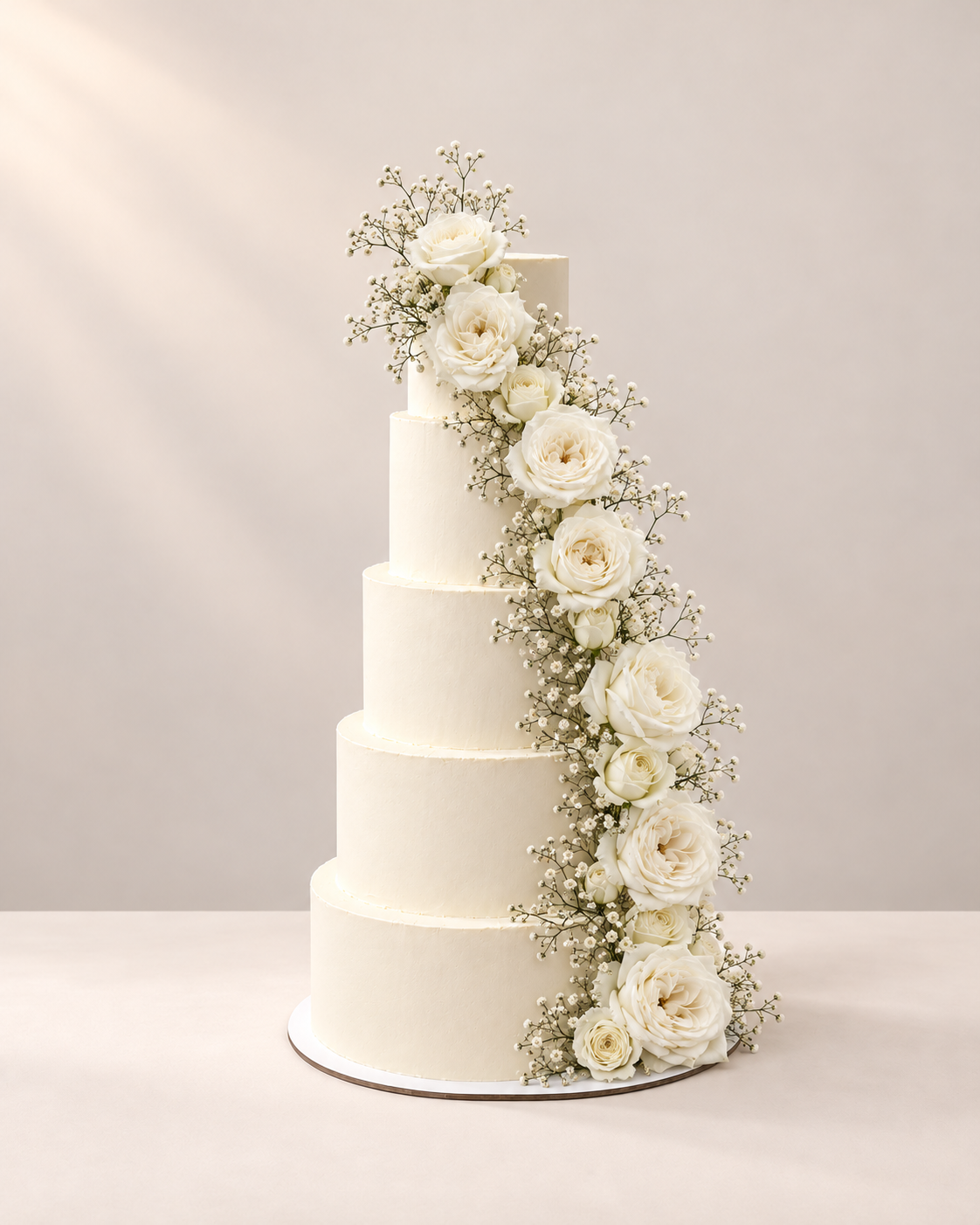 Pièce montée de cinq étages ornée de roses blanches et de gypsophile en cascade