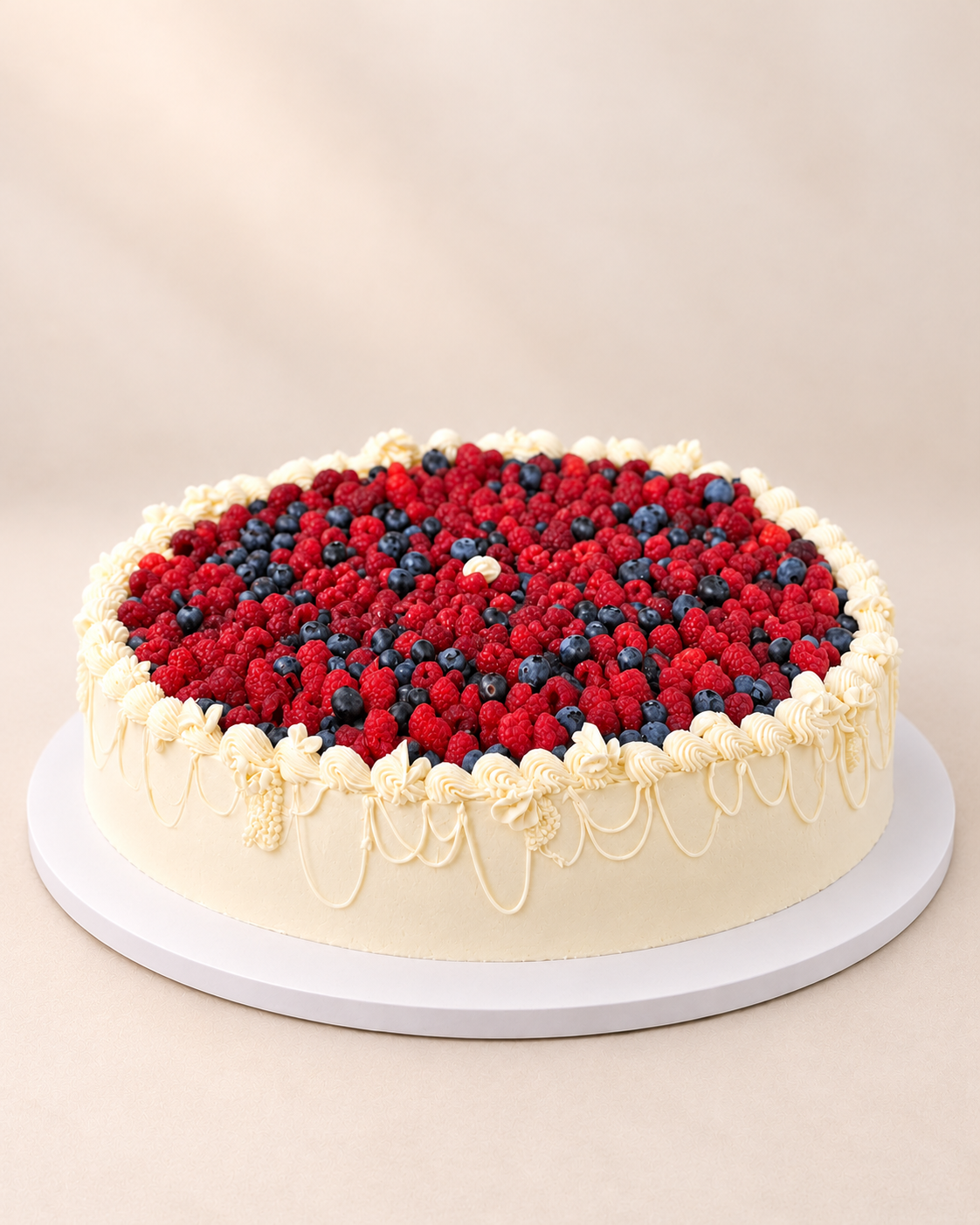 Gâteau de mariage rond aux framboises et myrtilles, décor de crème ivoire