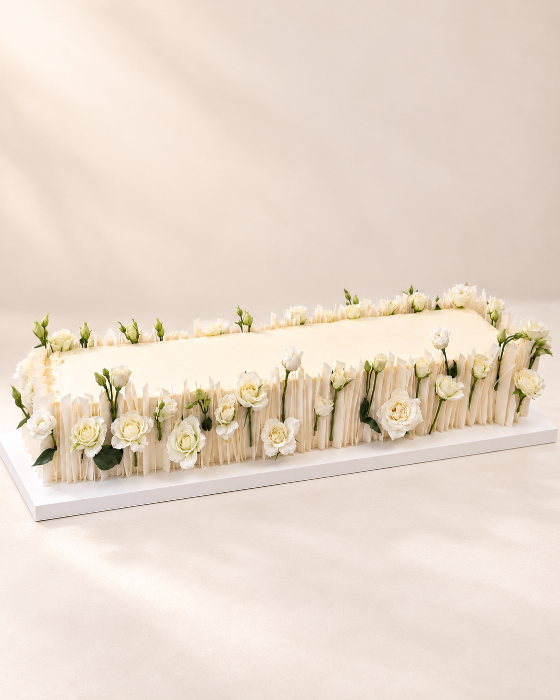 Gâteau de mariage long aux roses blanches